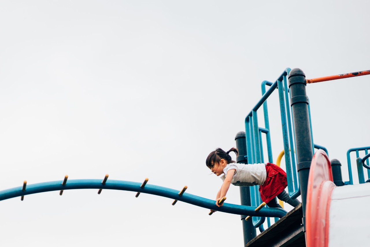 3 year old girl playing with playground equipment